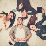 39255027 – happy multiracial friends relaxing on a carpet with gadgets